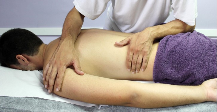 Mann liegt auf einer Liege und wird vom Physiotherapeut behandelt